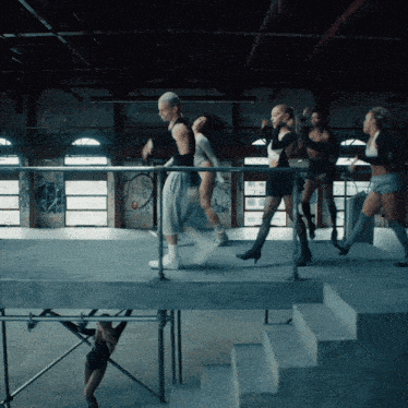 a group of female dancers are dancing in a room with graffiti on the walls
