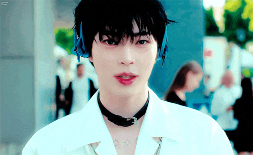 a young man wearing headphones and a choker is looking at the camera