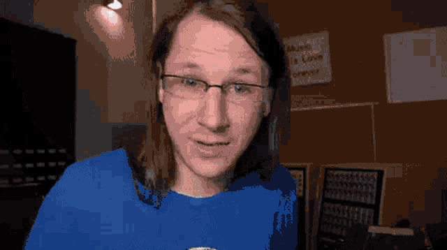 a man wearing glasses and a blue shirt is looking at the camera in front of a sign that says music is love forever .