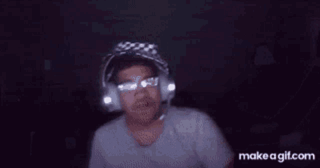 a man wearing headphones is dancing in a dark room .