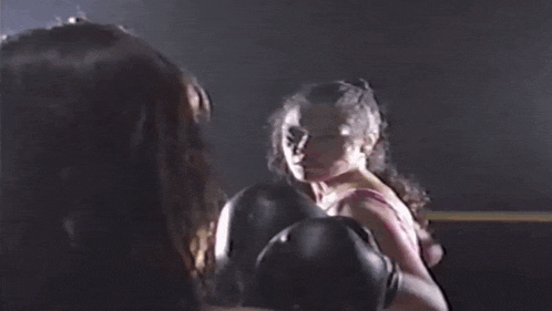 a woman in a pink bra is boxing another woman in a ring .