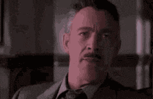 a man is sitting at a desk in front of a mirror looking at himself .