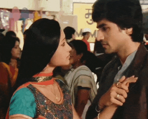 a man and a woman are looking at each other in a crowded area with a sign in the background that says " m "