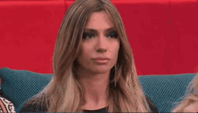 a woman is sitting on a couch with her eyes closed and making a funny face .
