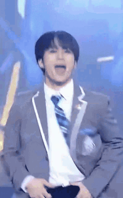 a man in a suit and tie is dancing on stage .