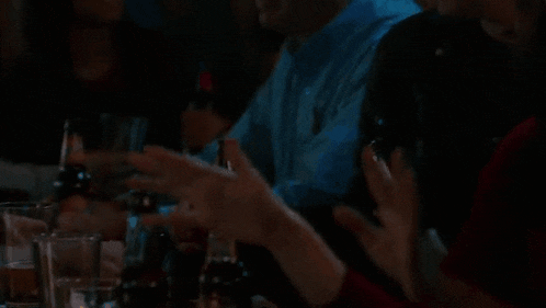a woman in a red dress is sitting in a dark room with her hand up in the air .