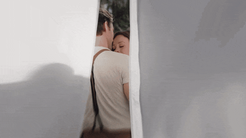 a man and woman are hugging behind a white curtain .