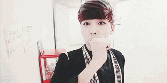 a young man with a scarf around his neck is brushing his teeth with a toothbrush