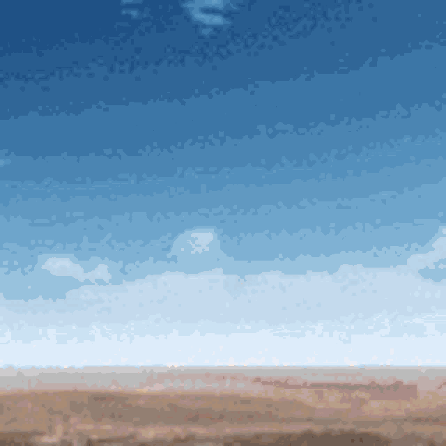 a blurry picture of a desert with a blue sky in the background
