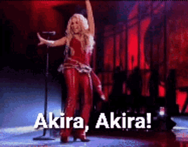 a woman in a red outfit is singing into a microphone and says akira akira !
