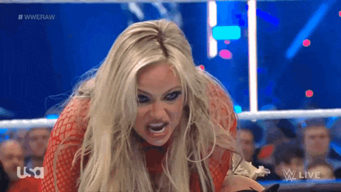 a woman in a red dress is screaming during a wrestling match