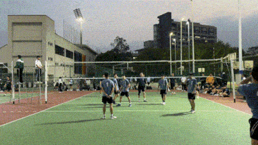 a group of people are playing volleyball on a court with a building in the background that says ok