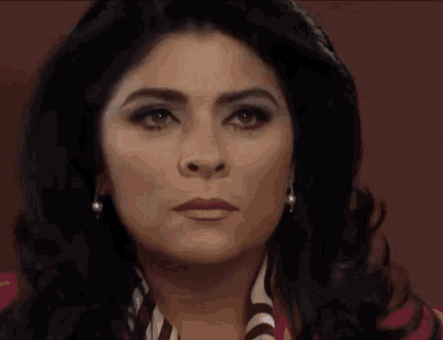 a close up of a woman 's face with a serious look on her face and earrings .