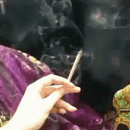 a person is smoking a cigarette in front of a purple blanket .