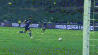 a soccer player kicking a ball on a field with a sign that says indian super league in the background