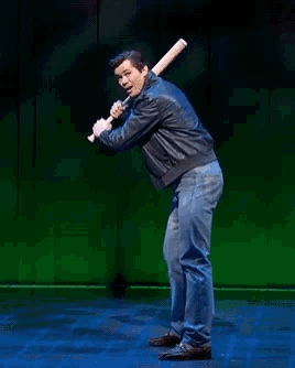 a man in a leather jacket is holding a baseball bat behind his back
