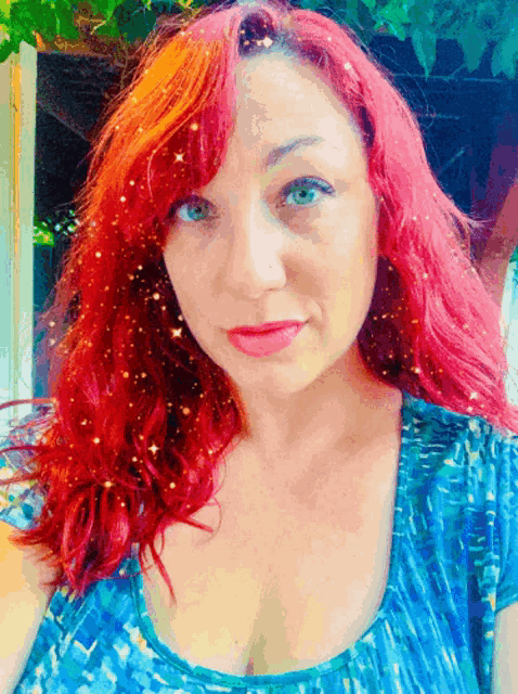a woman with red hair and blue eyes wearing a blue top
