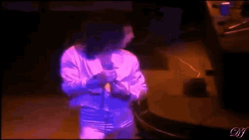 a man in a white shirt is singing into a microphone while standing on a stage .
