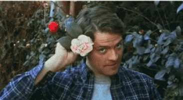 a man in a plaid shirt is holding a flower in his hand .