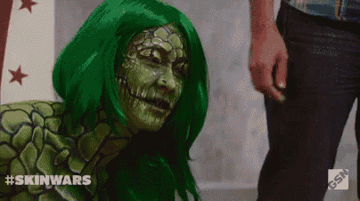 a woman in a green wig is standing next to a man in black pants .