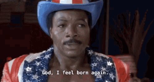 a man wearing a cowboy hat and an american flag shirt says `` god , i feel born again . ''