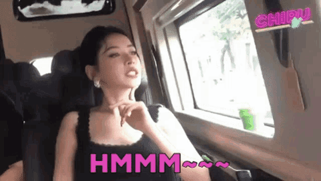a woman is sitting in a car next to a window and talking .