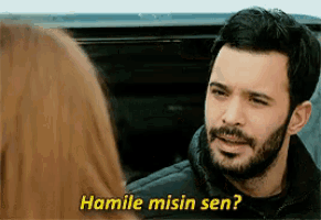 a man with a beard is talking to a woman and says hamile misin sen .