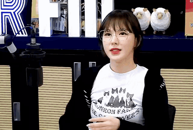 a girl wearing glasses and a t-shirt that says tomorrow fans are sitting in front of a microphone .
