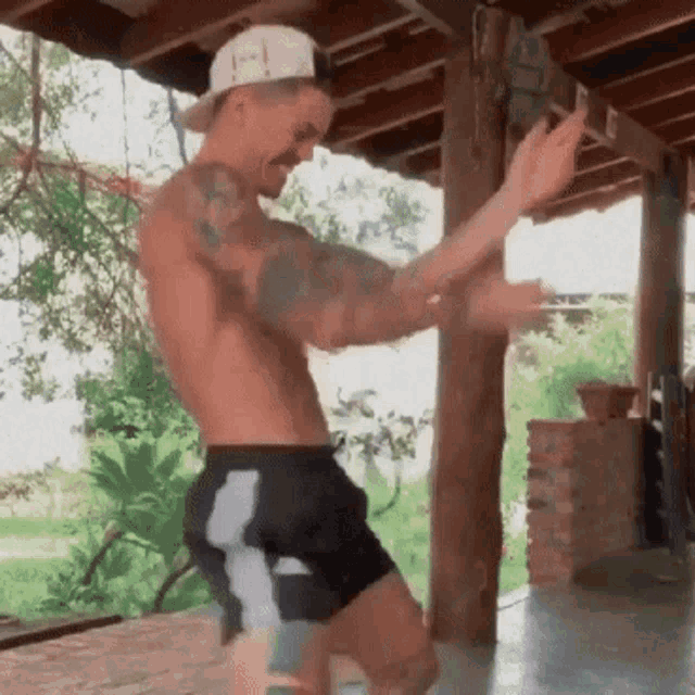 a shirtless man with tattoos is dancing on a porch .