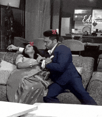 a man in a suit is sitting on a couch with a woman in a dress