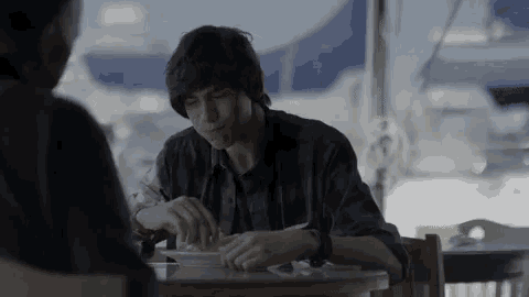 a young man is sitting at a table with a woman and eating a meal .