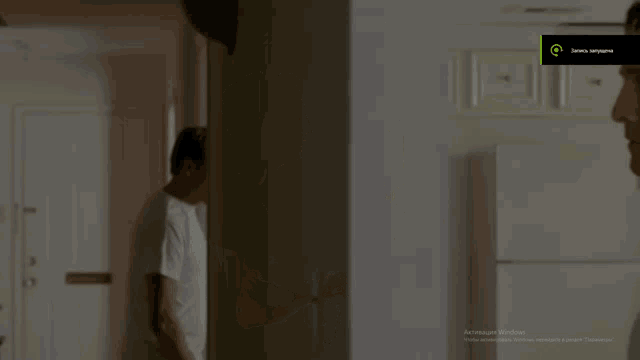 a man in a white tank top stands in front of a window with vertical blinds and a screen that says " activate windows "
