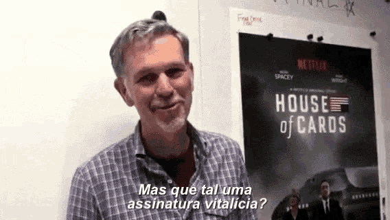 a man is standing in front of a house of cards poster .