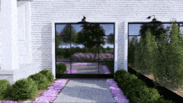 a white brick building with a black door and purple flowers
