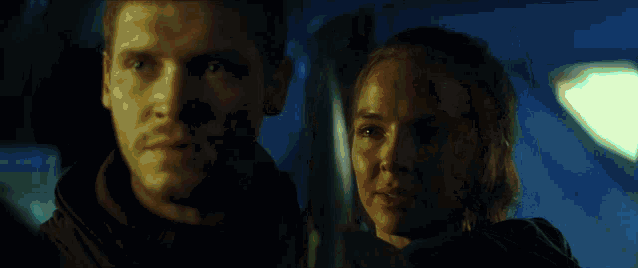a man and a woman look at each other in a dark room