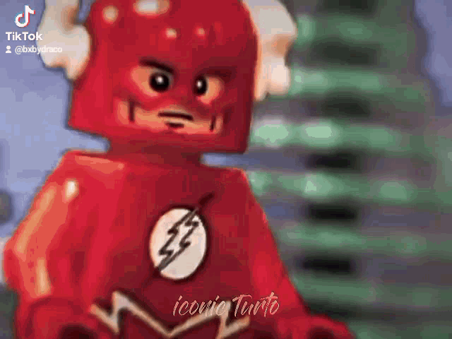 a lego flash is standing in front of a building in a video .