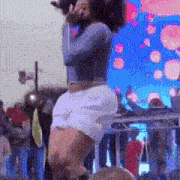 a woman is standing on a stage holding a microphone in front of a crowd of people .
