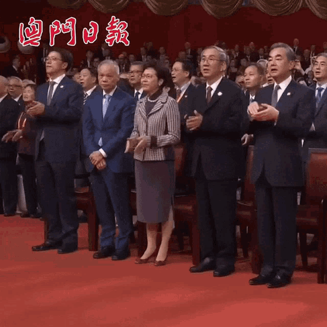a group of people standing on a red carpet with chinese writing on the back