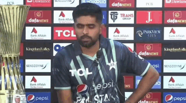a man wearing a tcl shirt is standing in front of a trophy