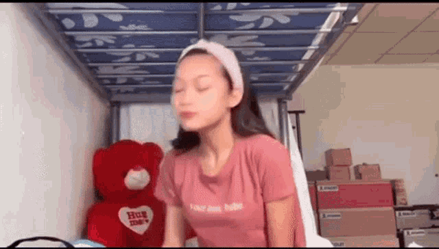 a girl is sitting in a bunk bed next to a teddy bear and boxes .