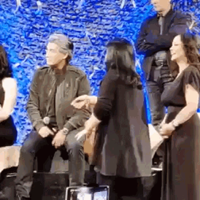 a group of people are standing around a stage talking to each other .