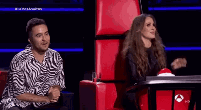a man in a zebra print shirt sits next to a woman