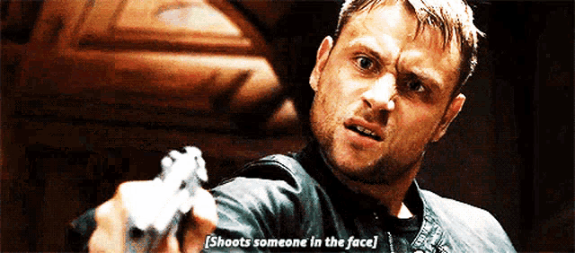 a man is pointing a gun at the camera and says shoots someone in the face .