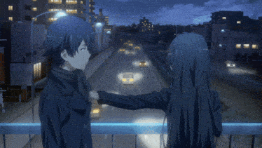 a boy and a girl are standing on a bridge looking at a highway at night