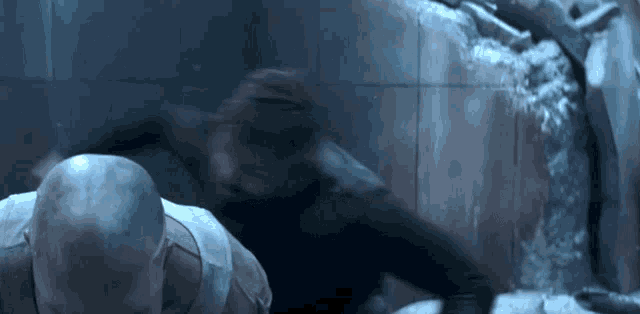 a man with a bald head is standing next to another man in a dark room