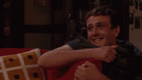 a man is sitting on a red couch with a pillow on his lap