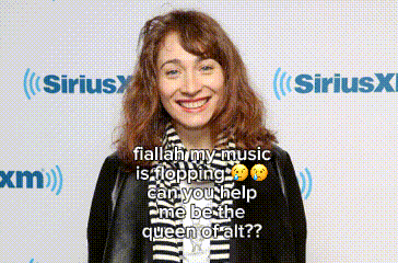 a woman is smiling in front of a sirius x radio station