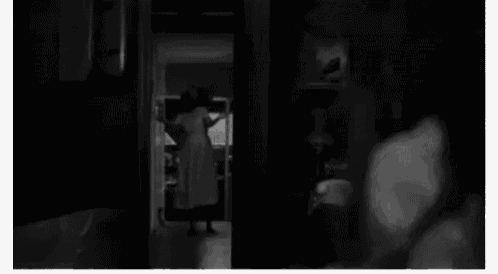 a black and white photo of a person walking down stairs in a dark room .