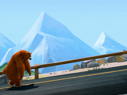 a bear is walking down a road in front of a mountain