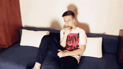 a man is sitting on a couch wearing a t-shirt that says anna